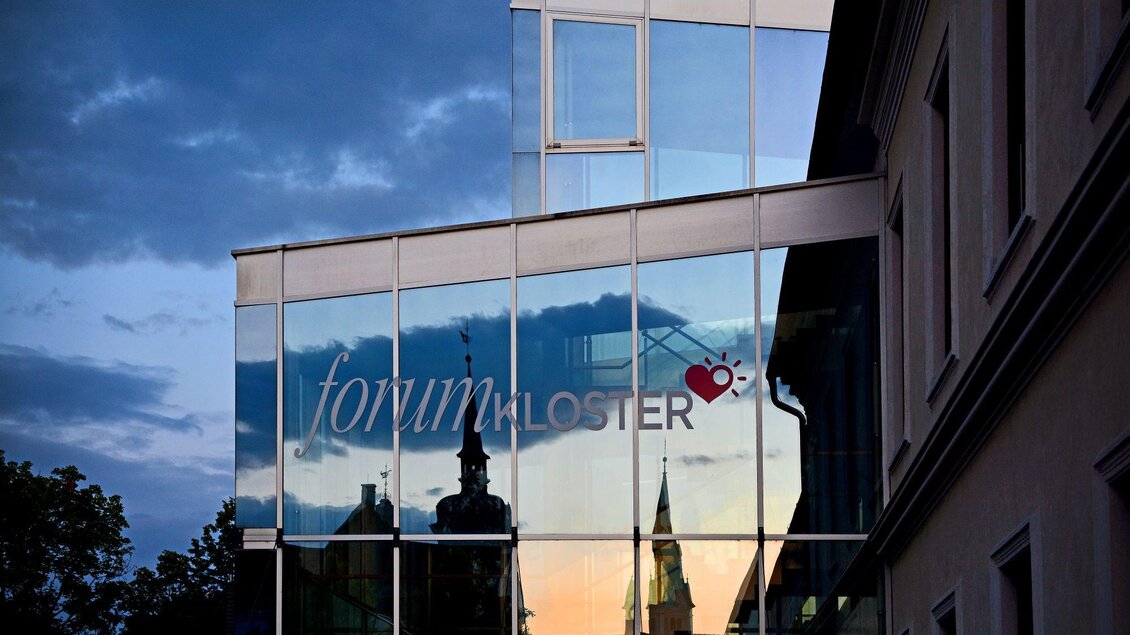 Im Glas des Eingangs vom forumKLOSTER spiegelt sich die Silhouette des schönen, alten Rathauses von Gleisdorf. | © Tourismusverband Oststeiermark