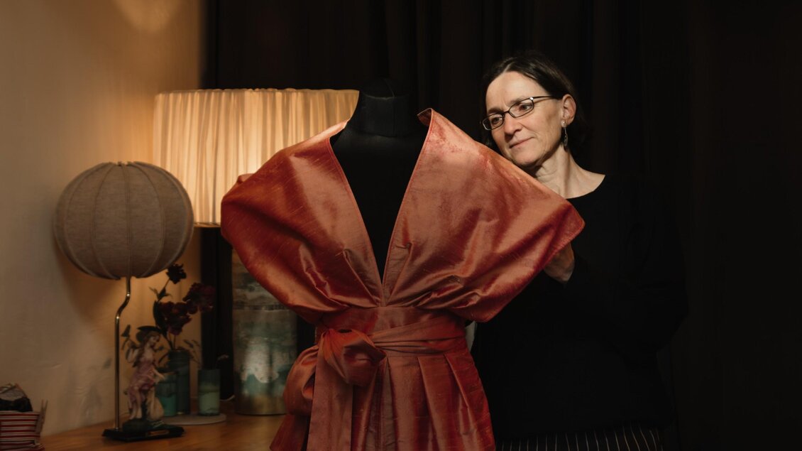 Barbara Stölzl präsentiert ein rot schimmerndes Kleid von Einzelstyck auf einer Schneiderpuppe. | © Bernd Grosseck