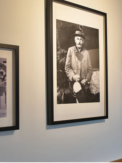 Drei gerahmte Schwarz-Weiß-Fotos hängen an einer hellen Wand. Die Bilder zeigen alte Architektur und eine Person in traditioneller Kleidung. | © event-fotograf.at