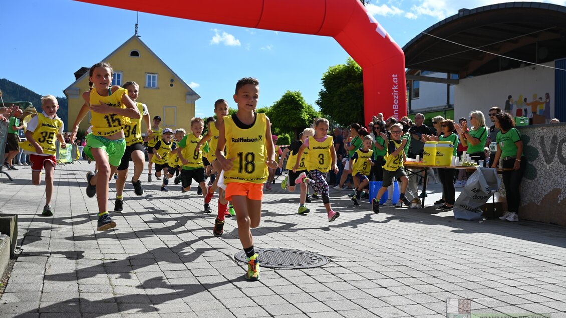 Eine Gruppe von Kindern läuft an einem Startbogen vorbei. Sie tragen leuchtende Trikots und die Stimmung ist lebhaft und fröhlich. | © Marktgmeinde Kraubath a.d.Mur