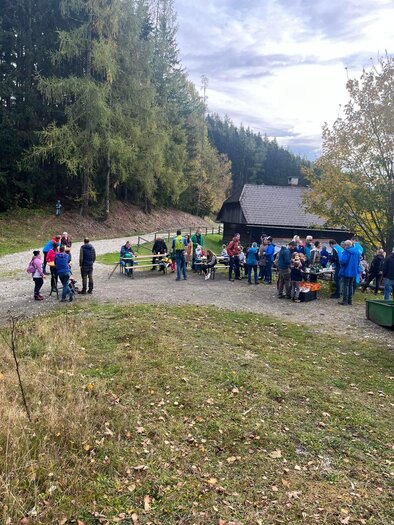 Eine Gruppe von Menschen versammelt sich im Freien, umgeben von Bäumen und einer Hütte. Es scheint eine gesellige Veranstaltung in der Natur zu sein. | © SV Union Mautern