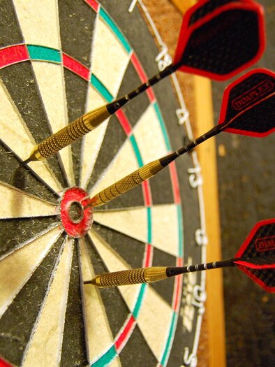 Eine Dartboard mit mehreren Pfeilen, die auf die Zielscheibe zeigen. Die Farben sind schwarz, rot und grün. | © pixabay.com