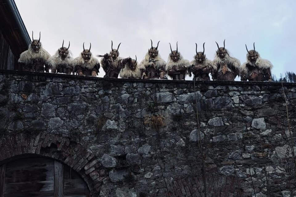 Gruppe von maskierten Figuren mit Hörnern auf einer Steinmauer. Sie tragen pelzartige Kostüme und blicken auf die Kamera. | © Zeiritz Teifln