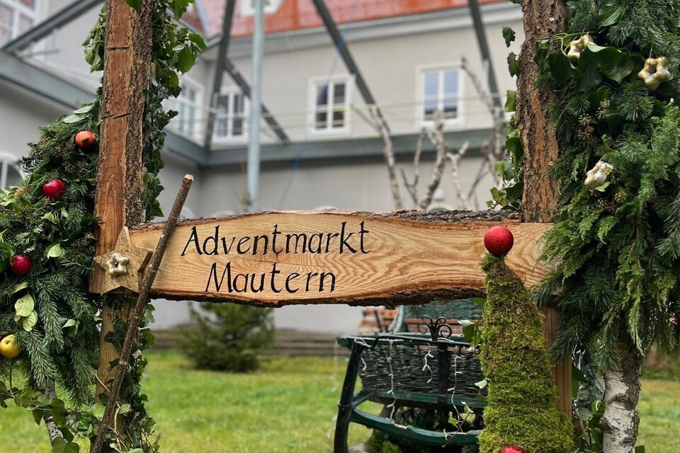Eine weihnachtliche Christbaumkugel in Rot mit einer winterlichen Landschaft. Das Ornament zeigt ein kleines Haus und einen Baum auf einer schneebedeckten Fläche. | © Hirt Wolfgang