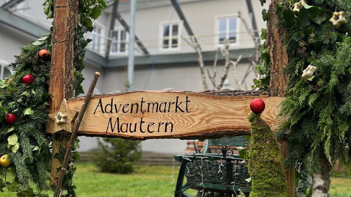 Eine weihnachtliche Christbaumkugel in Rot mit einer winterlichen Landschaft. Das Ornament zeigt ein kleines Haus und einen Baum auf einer schneebedeckten Fläche. | © Hirt Wolfgang