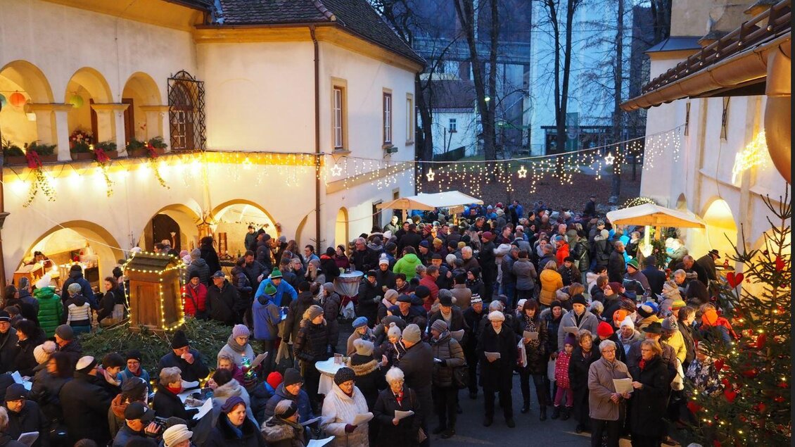 Eine große Menschenmenge versammelt sich in einer festlich dekorierten Gasse. Es ist dunkel, und es hängen Lichter und Weihnachtsdekorationen überall. | © Wolfgang Gaube