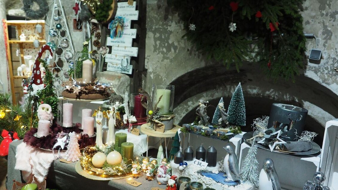Ein festlich dekorierter Tisch mit verschiedenen Weihnachtsartikeln und Kerzen. Es gibt zahlreiche dekorative Figuren und grüne Pflanzen. | © Wolfgang Gaube