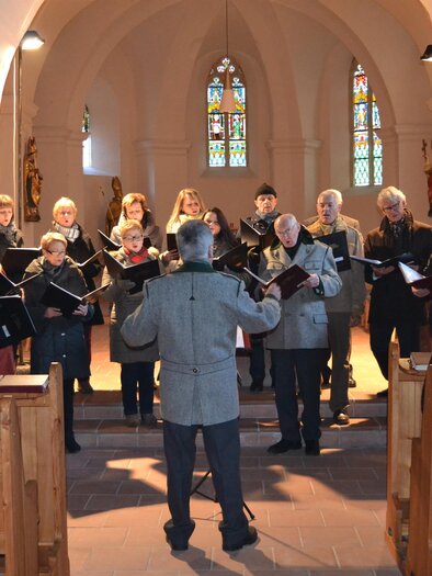 Ein Chor singt in einer Kirche. Die Zuschauer sitzen auf Holzbänken und lauschen der Musik. | © Karl Dobnigg