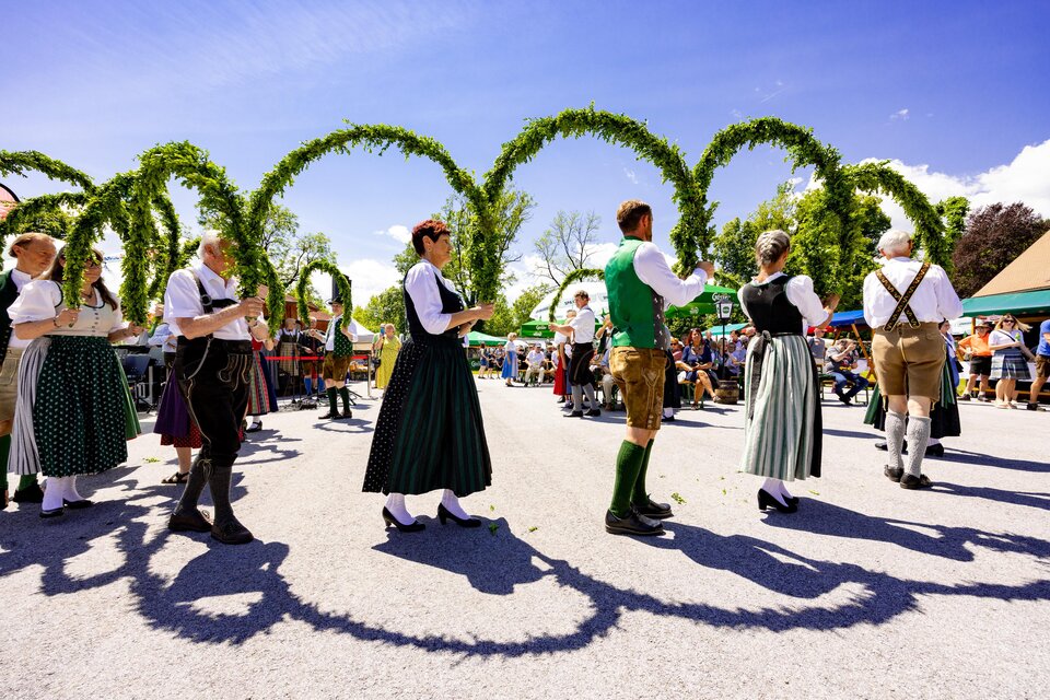 Volkstanzgruppe in Tracht tanzt mit grünen Bögen bei der Steirischen Roas in St. Bartholomä vor Publikum. | © Region Graz-Harry Schiffer
