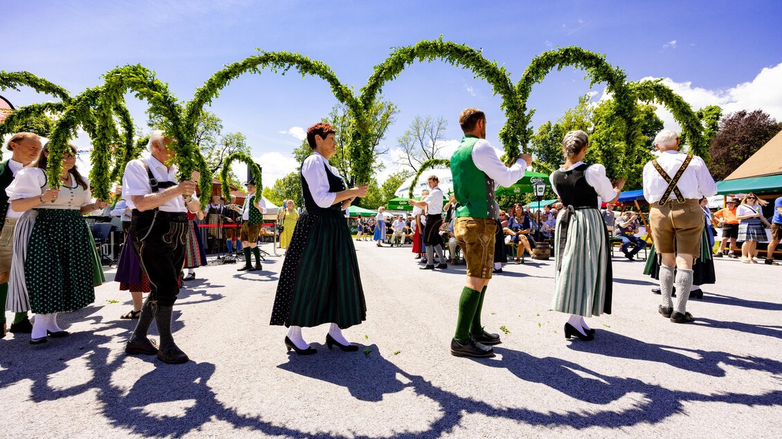 Volkstanzgruppe in Tracht tanzt mit grünen Bögen bei der Steirischen Roas in St. Bartholomä vor Publikum. | © Region Graz-Harry Schiffer