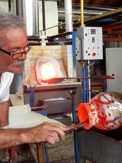 Glaskünstler Heinz Strasser formt an der Glasmacherpfeife ein glühendes, mundgeblasenes Glas in der Werkstatt. | © GlasMuseum Bärnbach