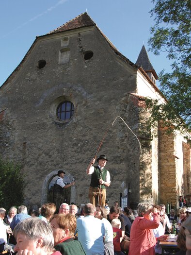 Eine belebte Freiluftveranstaltung vor einem historischen Gebäude. Menschen versammeln sich und genießen die Atmosphäre. | © Trachtenverband Mürztal