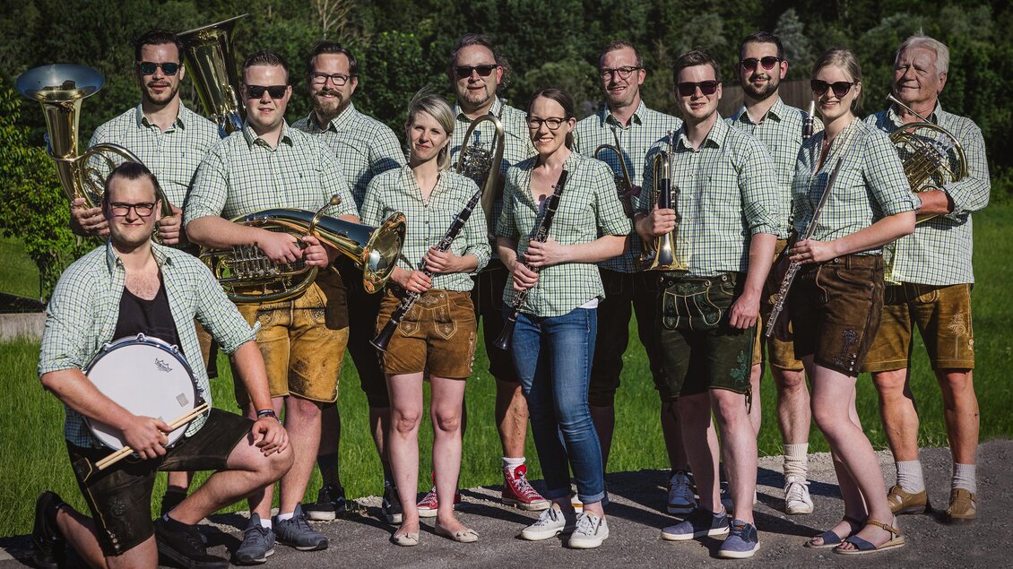 Eine Gruppe von Musikern in traditioneller Tracht steht im Freien. Sie spielen verschiedene Blasinstrumente und lächeln in die Kamera. | © (c) Martin Benedikt