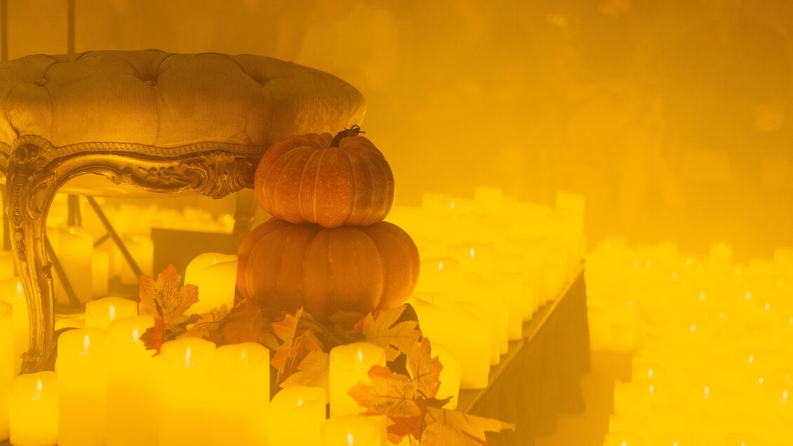 Kerzenmeer mit herbstlicher Dekoration aus Kürbissen und Blättern bei einem Candlelight-Konzert. | © feverup.com