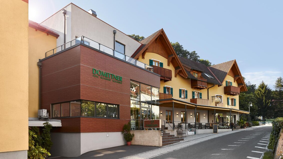 Ein modernes Gebäude mit einer Kombination aus Holz und Stein. Es ist gut beleuchtet und umgeben von Bäumen. | © Hotel Domittner