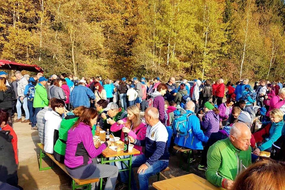 Eine Menschenmenge versammelt sich im Freien, um die herbstliche Landschaft zu genießen. Viele Personen sitzen an Tischen und essen oder trinken. | © TVB Erzberg-Leoben