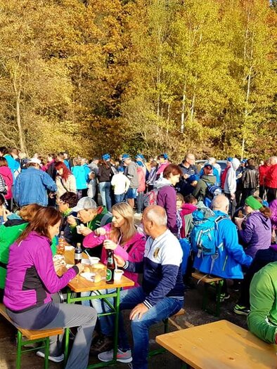 Eine Menschenmenge versammelt sich im Freien, um die herbstliche Landschaft zu genießen. Viele Personen sitzen an Tischen und essen oder trinken. | © TVB Erzberg-Leoben
