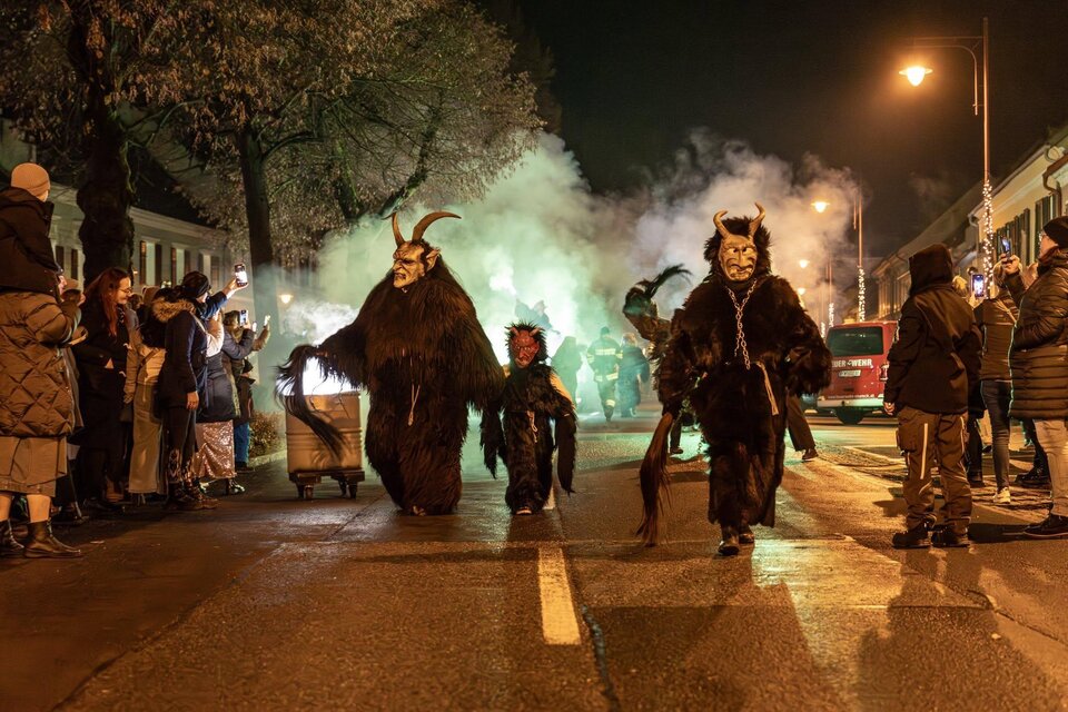 Eine nächtliche Parade mit Menschen in auffälligen Kostümen. Es gibt rauchige Effekte und Zuschauer am Straßenrand. | © Foto de Monte Mureck
