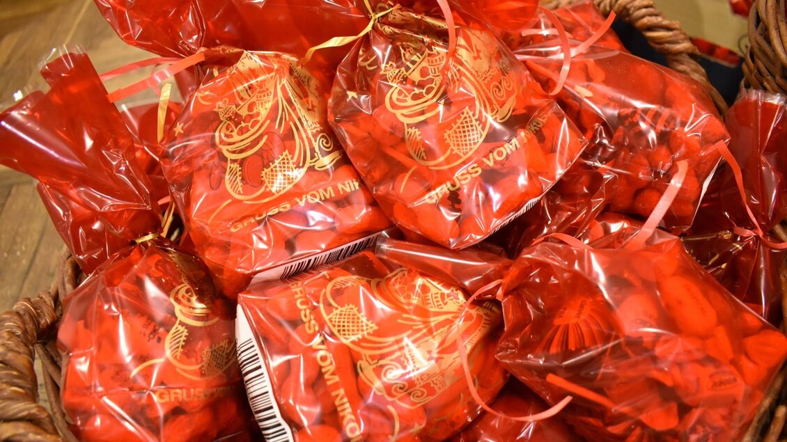 Rote Tütchen voller Süßigkeiten sind in einem Korb angeordnet. Die Tütchen sind kunstvoll verpackt und verleihen dem Bild ein festliches Aussehen. | © Foto de Monte Mureck