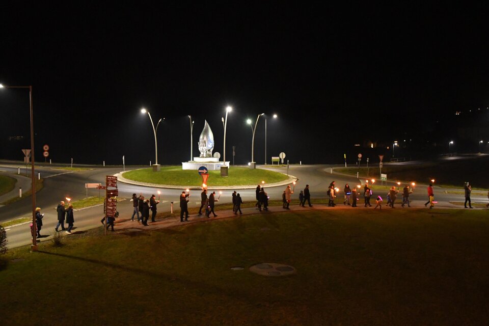 Eine Gruppe von Menschen läuft mit Fackeln um einen Platz bei Nacht. In der Mitte steht eine Statue, und die Umgebung ist schwach beleuchtet. | © H2O Hoteltherme GmbH