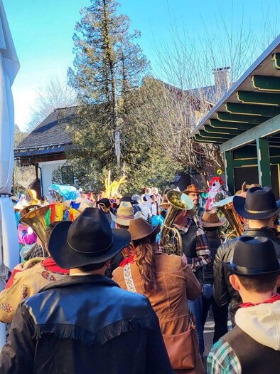 <p>The different carnival groups from the carnival parade in Altaussee gather outside. In the background, the mountains of Ausseerland and a clear, blue sky can be seen.</p> | © Petra Kirchschlager