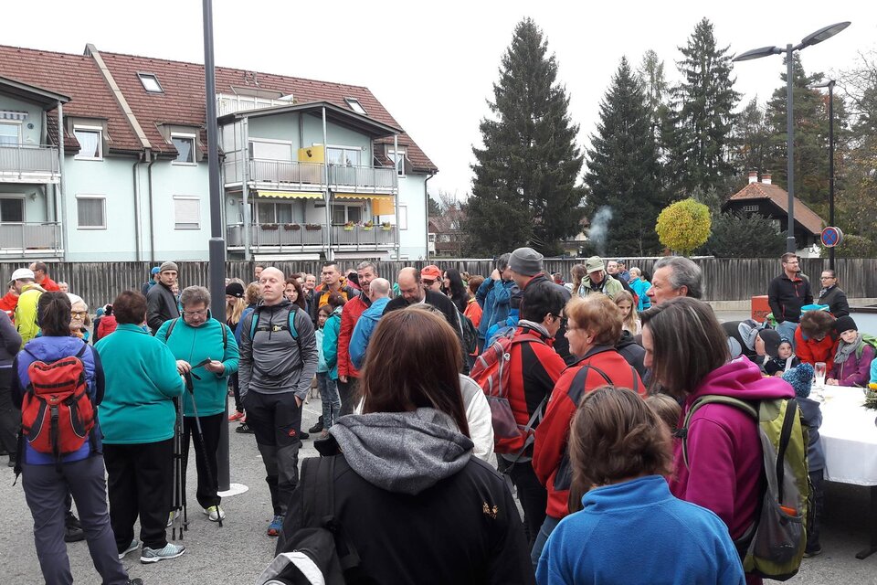 Eine große Gruppe von Menschen versammelt sich auf einem Platz. Viele tragen Wanderkleidung und es sind einige Gebäude im Hintergrund sichtbar. | © Stadtgemeinde Trofaiach