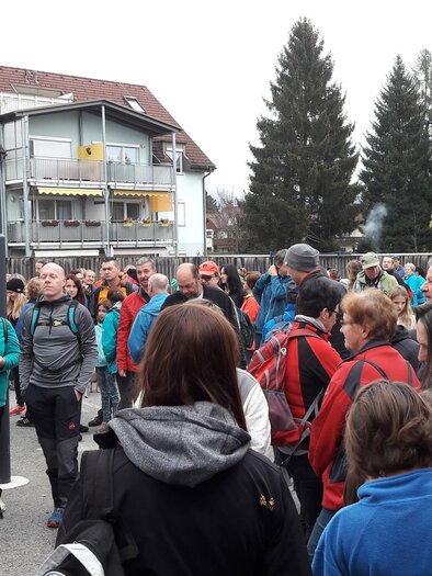 Eine große Gruppe von Menschen versammelt sich auf einem Platz. Viele tragen Wanderkleidung und es sind einige Gebäude im Hintergrund sichtbar. | © Stadtgemeinde Trofaiach