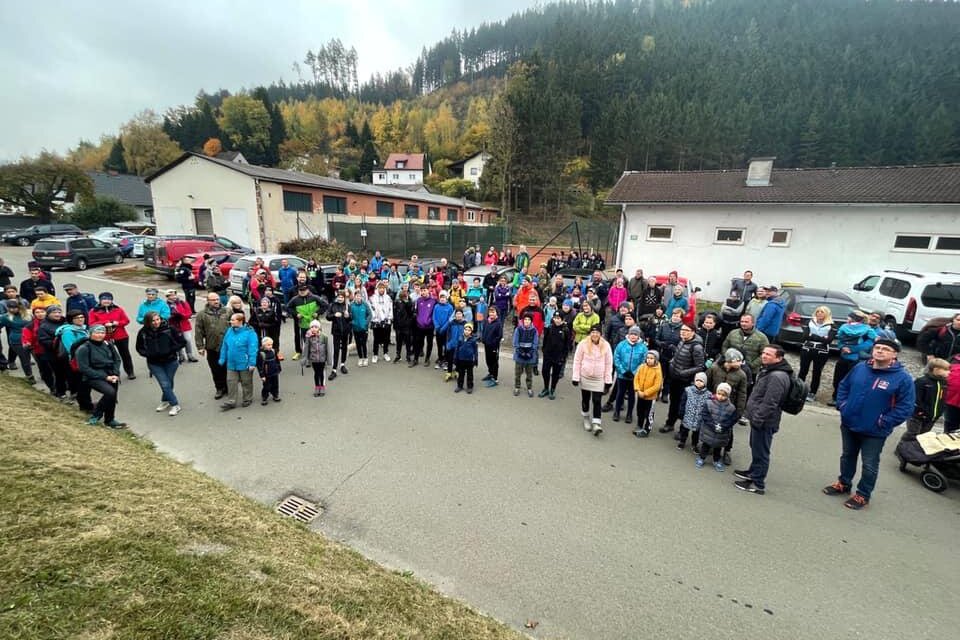 Eine große Gruppe von Menschen versammelt sich draußen auf einem Parkplatz. Sie tragen bunte Kleidung und scheinen an einem Event oder einer Veranstaltung teilzunehmen. | © ATUS Niklasdorf