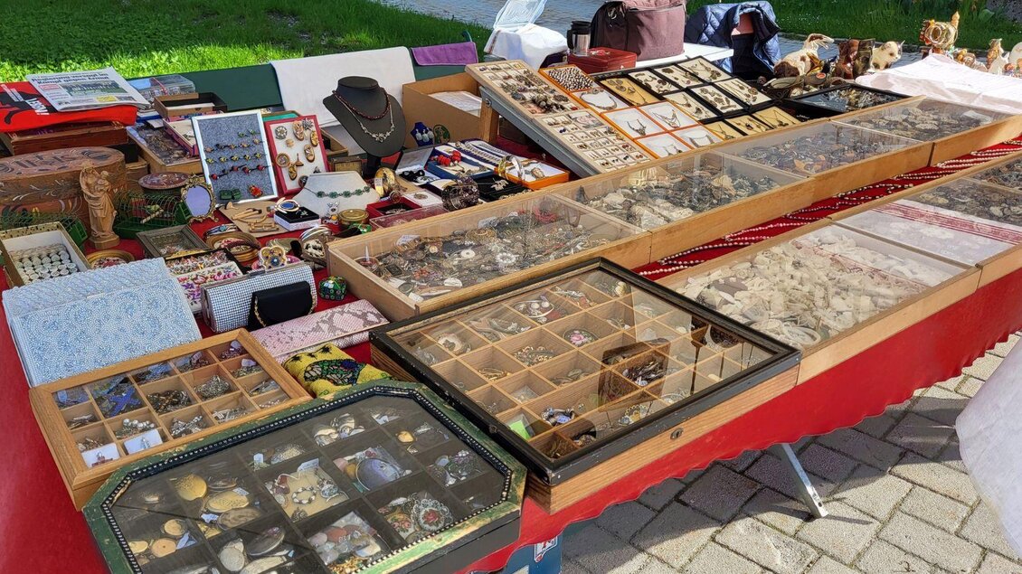 Ein bunter Marktstand mit verschiedenen Schmuckstücken und handgefertigten Kunstwerken. Die Auslage zeigt viele kleine Kästchen voller Schmuck und Zierden. | © Petra Kirchschlager
