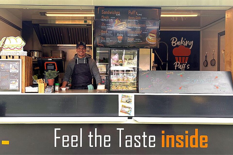 Koch hinter dem Verkaufstresen eines Foodtrucks mit Sandwiches und weiteren Speisen in Seiersberg-Pirka. | © foodandfunfestival.at