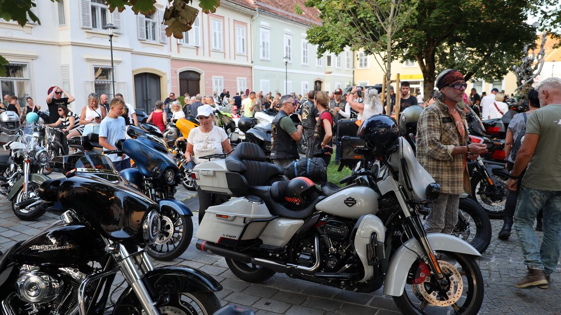 Eine belebte Straßenszene mit vielen Motorrädern und Menschen. Die Atmosphäre ist festlich und voller Begeisterung. | © Zehnerhaus