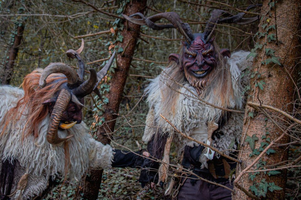 Zwei mystische Kreaturen mit Hörnern und pelzigen Kostümen stehen im Wald. Sie wirken geheimnisvoll und furchterregend zwischen den Bäumen. | © Übelbacher Gleinalm Pass