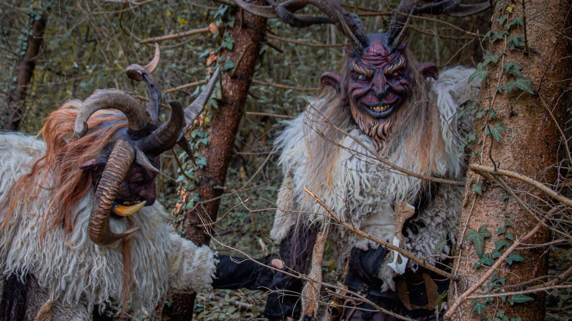 Zwei mystische Kreaturen mit Hörnern und pelzigen Kostümen stehen im Wald. Sie wirken geheimnisvoll und furchterregend zwischen den Bäumen. | © Übelbacher Gleinalm Pass