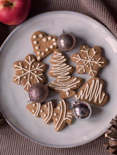 Ein Teller mit weihnachtlichen Keksen in Form von Sternen und Tannenbäumen. Umgeben von Äpfeln und Tannenzapfen. | © Annika Bitter auf Pixabay.