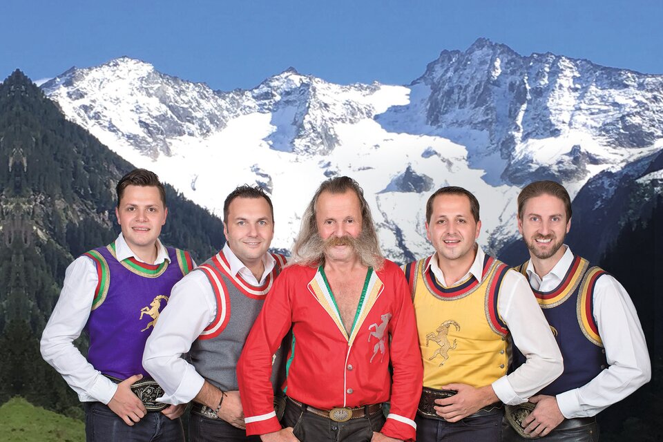 Fünf Musiker der Mayrhofner in Tracht vor alpiner Bergkulisse im Landcafé Kern, Weststeiermark. | © Die Mayerhofner