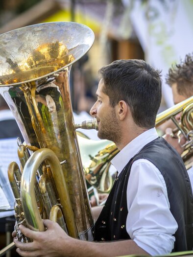 Musicians of a brass band play tuba and trombones at an outdoor concert. In front of them stand music stands. | © Ivents Kulturagentur-Erwin Scheriau