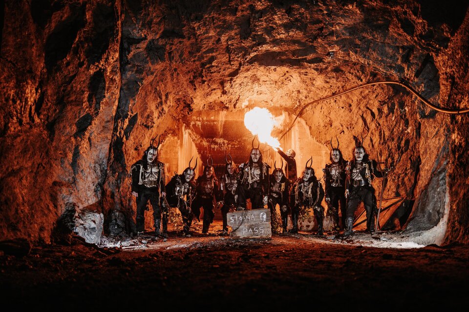 Eine Gruppe von Menschen steht in einer dunklen Höhle, umgeben von Felsen. Sie tragen auffällige Kostüme und schminken ihre Gesichter. | © Stoana Pass