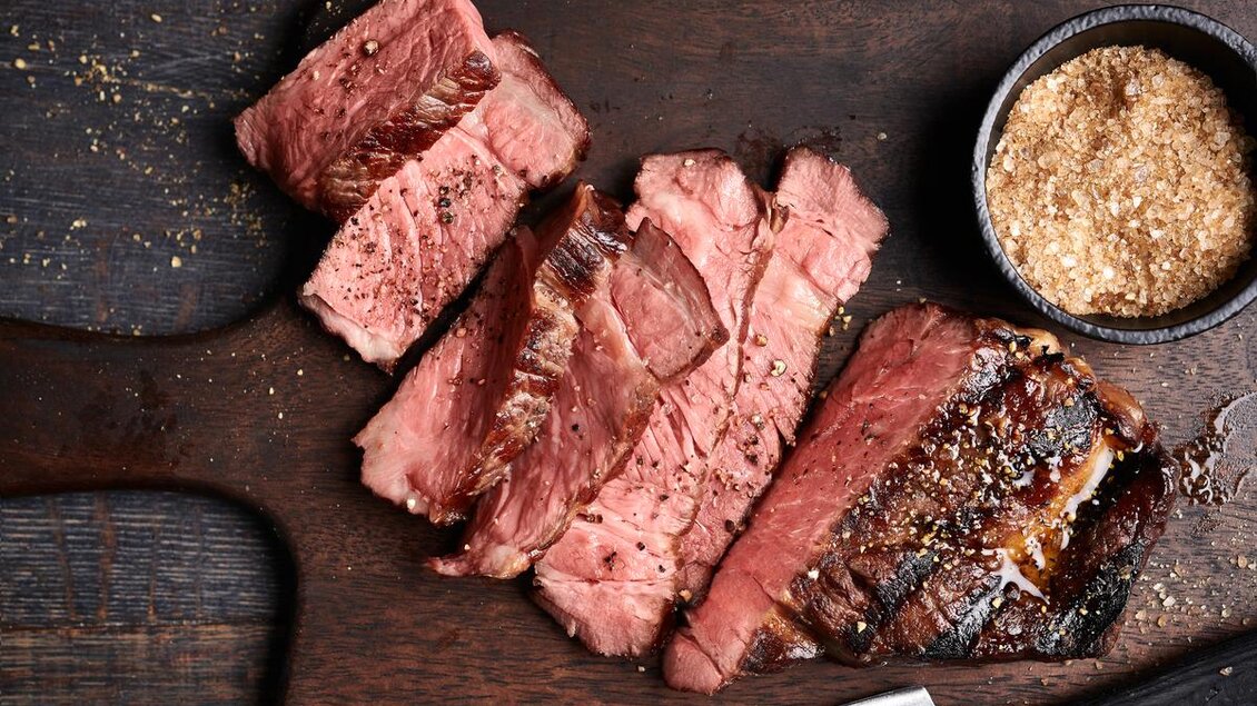 Aufgeschnittenes Steak auf einem Holzbrett mit Gewürzen beim Krimi & Dinner im Weber Grillcenter Graz. | © Weber Grillcenter