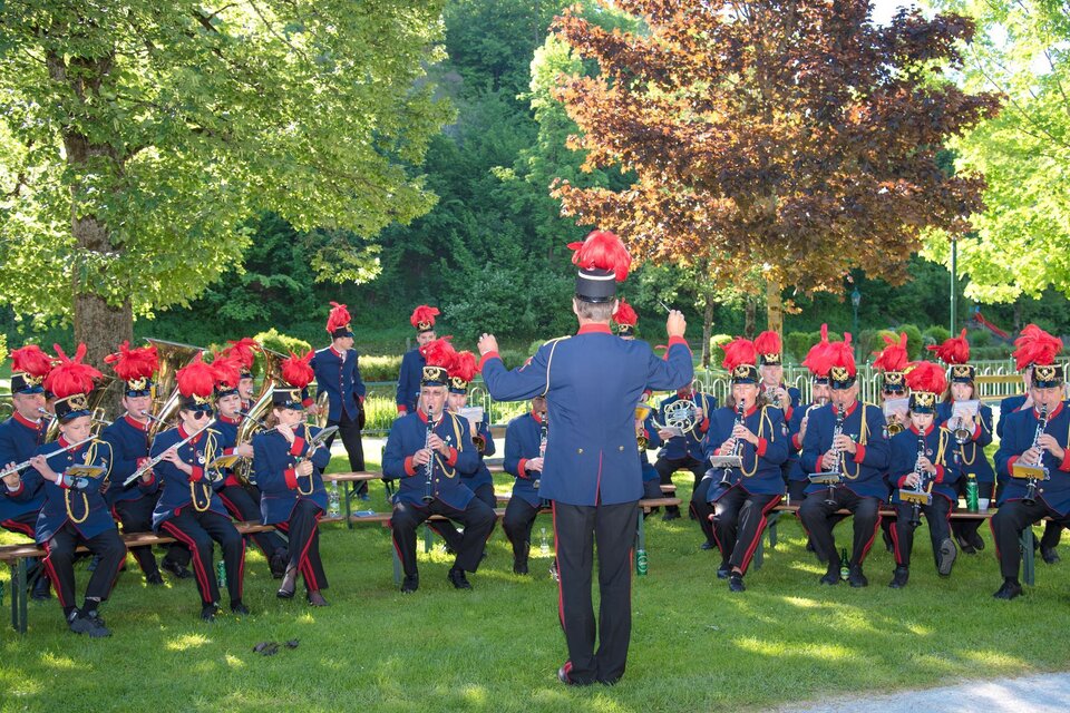 Musikkapelle Strassen, Bad Aussee spielt in Uniform und mit Hüten  im Freien. Der Dirigent steht vorne und leitet die Musiker. </p> | © www.narzissenfest.at