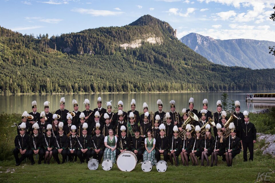 Die Salinenmusikkapelle Altaussee ist eine große Blasmusikkapelle. Die Mitgllieder der Salinenmusikkapelle stehen am Ufer des Altaussees, welcher von Bergen umgeben ist. Die Musiker tragen die traditionelle schwarze Uniform der Saline Altaussee und Hüte. 
 | © Erich Kainzinger