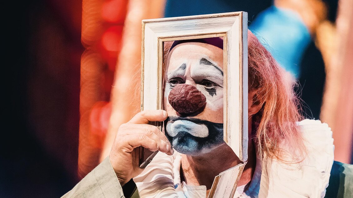 Clown mit weiß geschminktem Gesicht hält bei einer La Strada-Aufführung in Kalsdorf einen Bilderrahmen vor das Gesicht. | © Jolanda Hofmann