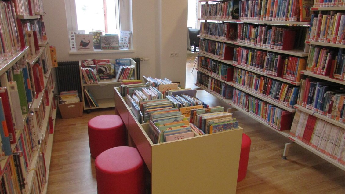 Eine gemütliche Bibliothek mit Regalen voller Bücher. In der Mitte stehen Tische mit Sitzkissen zum Lesen und Entspannen. | © Bücherei Bad Radkersburg