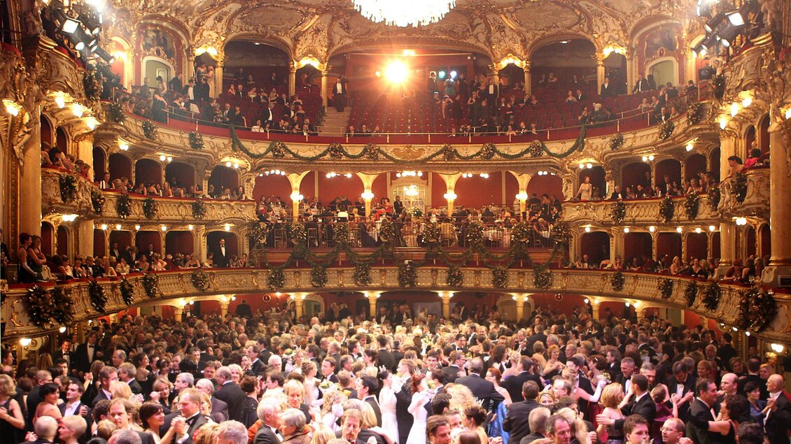 Ein eleganter Ballsaal mit vielen festlich gekleideten Gästen, die tanzen. Die opulente Architektur und die glänzenden Lichter schaffen eine festliche Atmosphäre. | © Marija Kanizaj