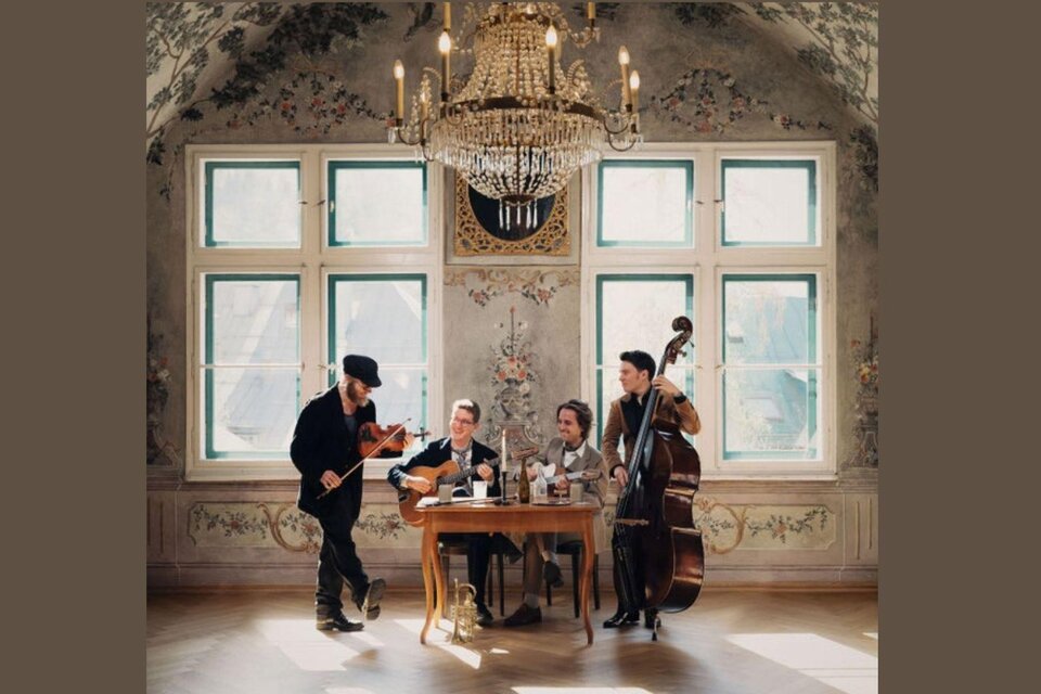 Eine musikalische Gruppe spielt in einem eleganten Raum mit einem Kronleuchter. Sie sitzen an einem Tisch und haben verschiedene Instrumente dabei. | © Kammerhofmuseum