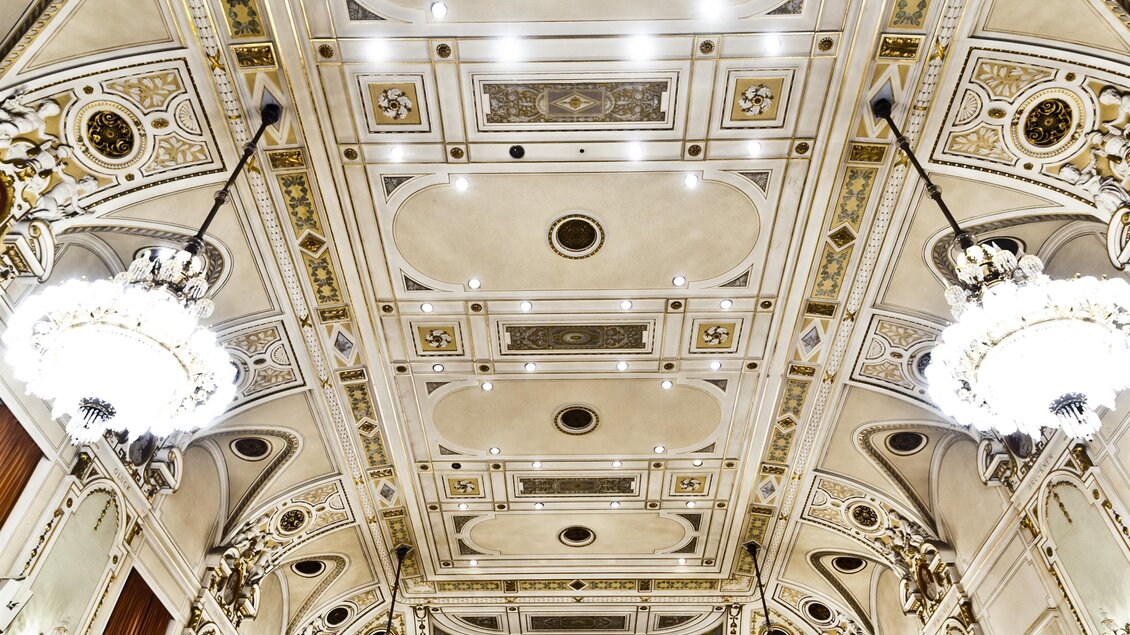 Ein prächtiger Veranstaltungssaal mit opulenter Decke und leuchtenden Kronleuchtern. Die Wände sind elegant verziert, was eine festliche Atmosphäre schafft. | © MCG - Werner Krug