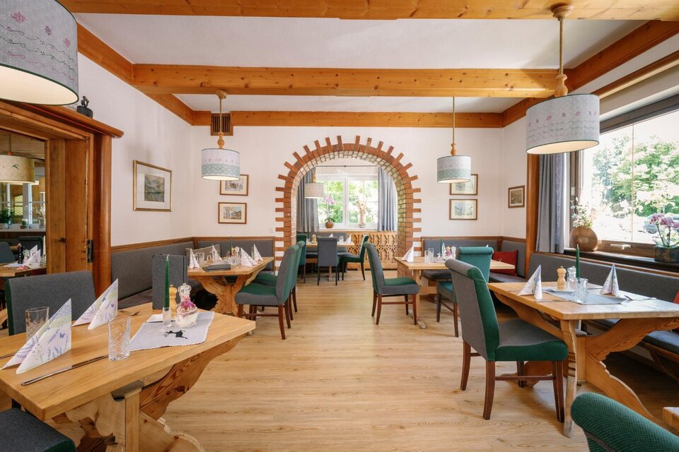 Ein einladendes Restaurant mit Holzdecke und gemütlichen Tischen. Helle Fenster ermöglichen einen Blick auf den Außenbereich. | © Karl Steinegger Fotografie