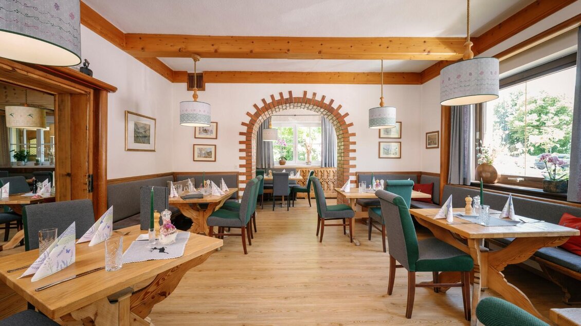 Ein einladendes Restaurant mit Holzdecke und gemütlichen Tischen. Helle Fenster ermöglichen einen Blick auf den Außenbereich. | © Karl Steinegger Fotografie