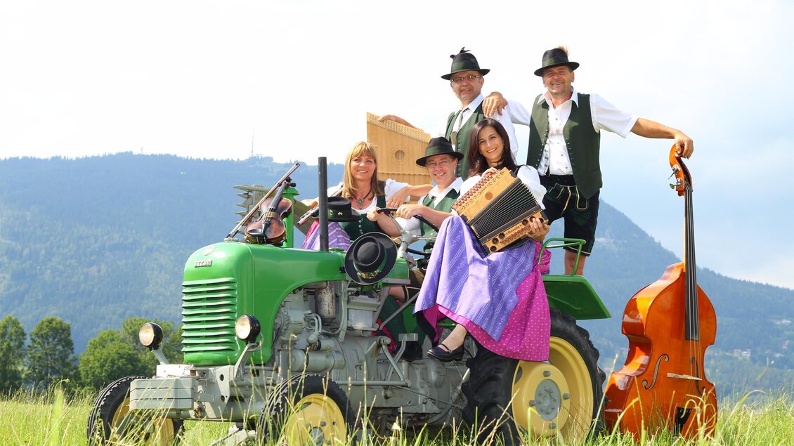 Musikgruppe in Tracht mit Knöpferlharmonika und weiteren Instrumenten auf einem Oldtimer-Traktor beim SUMT. | © Knöpferlstreich