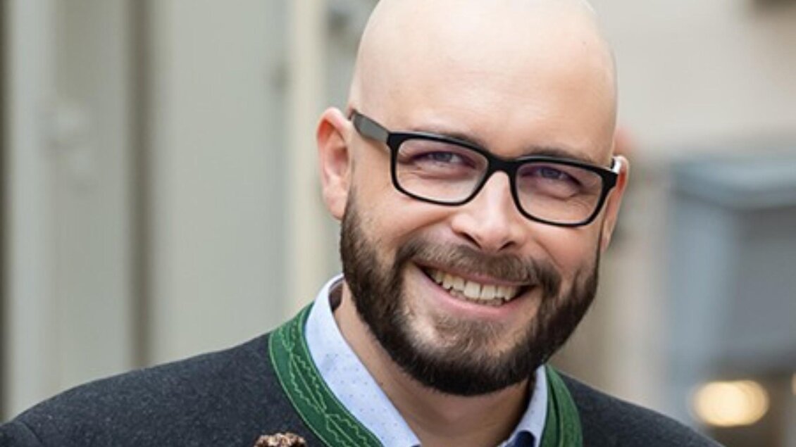 Porträt von Moderator Daniel Neuhauser in Trachtenjacke und Brille beim SUMT. | © ORF