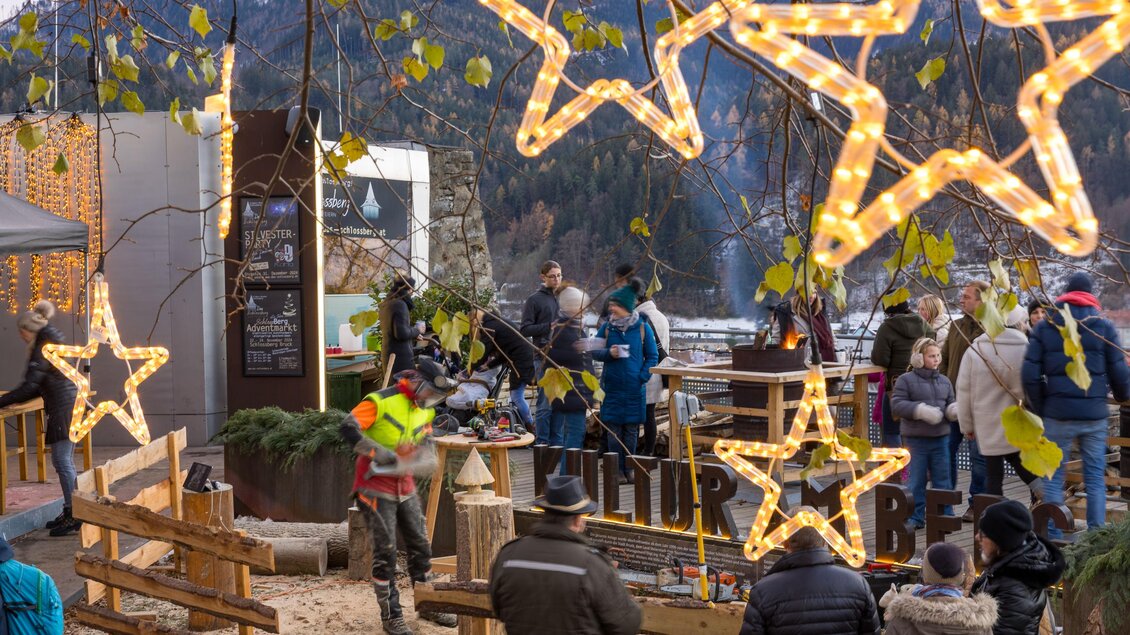 Eine festliche Szene mit leuchtenden Sternen und Menschen, die sich versammeln. Im Hintergrund sind Berge und Stände zu sehen, die eine gemütliche Atmosphäre schaffen. | © meieregger.photos